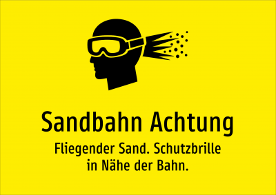 Sandbahn Achtung - Fliegender Sand. Schutzbrille in Nähe der Bahn.